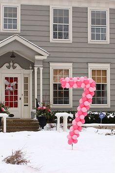 the number seven is made out of balloons in front of a house with snow on the ground