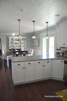 a kitchen with white cabinets and wood floors