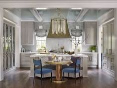 a dining room table and chairs in front of a chandelier over a kitchen island