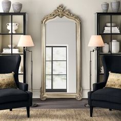 a living room with two chairs and a large mirror on the wall above it's windows