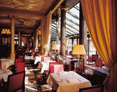 a restaurant with tables and chairs in front of large windows, along with yellow drapes