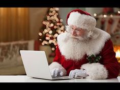 a santa clause sitting at a desk using a laptop computer