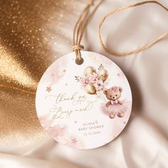 a pink and gold baby shower ornament with a teddy bear on it's back