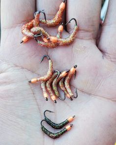 three different types of fishing lures on a person's hand, one is orange and the other is green