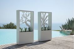 two white planters sitting on top of a wooden floor next to a swimming pool