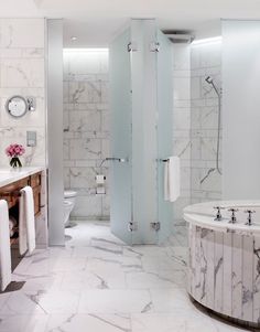 a bathroom with marble walls and flooring next to a bathtub in the corner