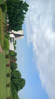 the house is surrounded by green grass and trees, with blue skies in the background