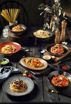 a table topped with plates of food on top of a wooden table next to utensils