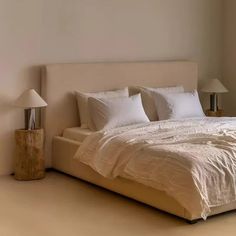 a bed with white sheets and pillows in a room