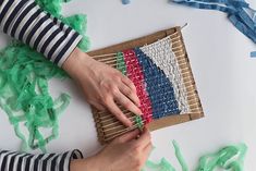 two hands are working on an american flag weaving project with green streamers around it