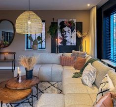 a living room filled with furniture next to a window covered in plants and candles on top of tables