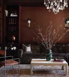 a living room filled with furniture and a chandelier hanging from the ceiling over a coffee table