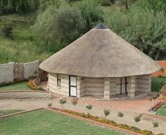 an aerial view of a round building with a thatched roof and garden in the foreground