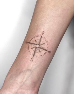 a small compass tattoo on the left inner forearm and wrist area is shown in black ink