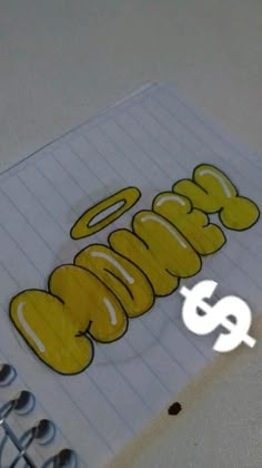 a spiral notebook with the word cookie written in yellow on it and two silver spoons next to it