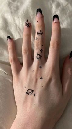 a woman's hand with black and white tattoos on her left palm, which has the planets and stars tattooed on it