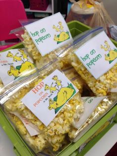 several bags of popcorn sitting on top of a green bin filled with cards that say hop on popcorn