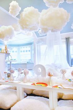 a room filled with lots of white furniture and clouds hanging from the ceiling above it