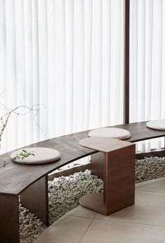 a curved bench sitting in front of a window next to a vase with flowers on it