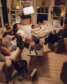 several people sitting on couches in a living room with christmas decorations and gifts around them