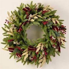 a christmas wreath hanging on the wall with holly and red berries, gold leaves and mists