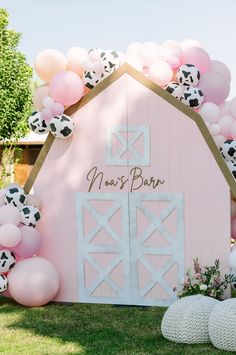 a pink barn decorated with balloons and farm animals