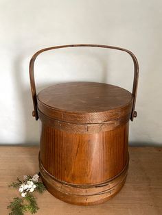 an old wooden bucket sitting on top of a table next to a small white flower