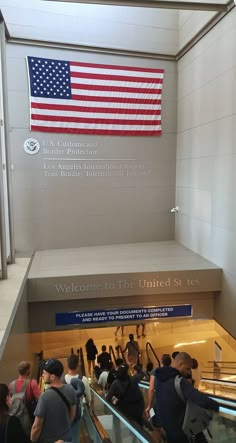 people are walking down an escalator with the american flag on it