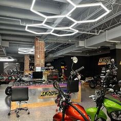 several motorcycles are parked in a showroom with lights hanging from the ceiling above them