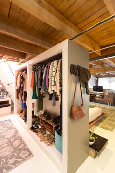 an open closet with clothes hanging on the wall and purses in front of it