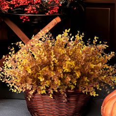 a basket filled with lots of yellow flowers next to pumpkins and other autumn decorations