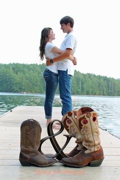 a man and woman standing next to each other on a dock with boots in front of them