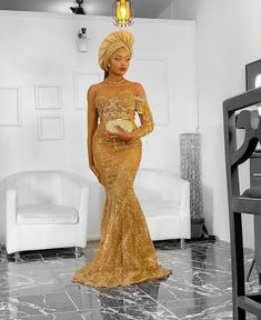 a woman standing in a room wearing a gold dress