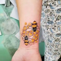 a woman with a tattoo on her wrist that has bees and honeycombs on it