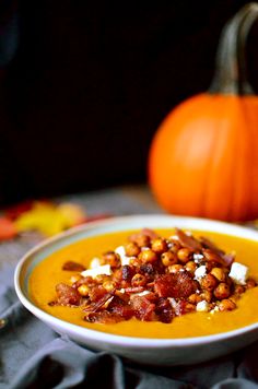 a white bowl filled with soup next to a pumpkin