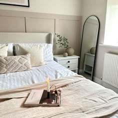 a bedroom with a bed, mirror and candles on the side table in front of it