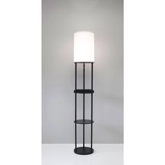 a black floor lamp with a white shade on it's head and shelf below