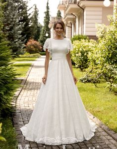 a woman in a white dress standing on a brick walkway