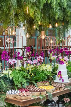 a table topped with lots of different types of cakes and flowers on top of wooden trays