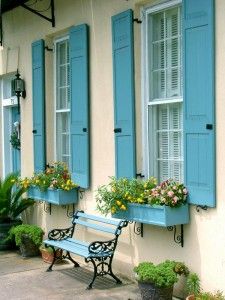 blue shuttered windows with flower boxes and bench in front