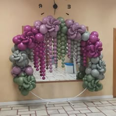 an arch made out of balloons in the shape of flowers is displayed on a wall