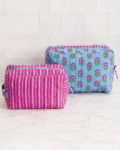 two blue and pink striped bags sitting on top of a white marble counter next to each other