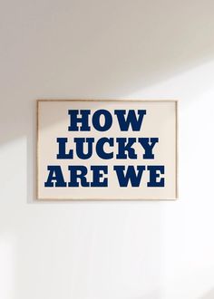 a poster that says how lucky are we? on the wall in a white room