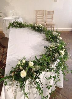 an arrangement of flowers and greenery on a white table cloth at a wedding reception