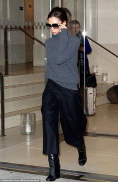 a woman in black pants and boots walking down stairs