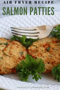 two crab cakes on a white plate with parsley garnish and a fork