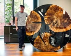 a man standing next to a large piece of wood on top of a hard wood floor