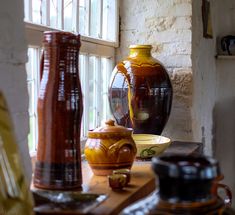 three vases sitting on top of a wooden table next to a window with shutters