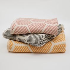 three towels stacked on top of each other in orange and grey colors, with one folded up