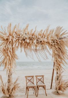 an outdoor wedding ceremony setup with pamodia and chairs on the beach in front of the ocean